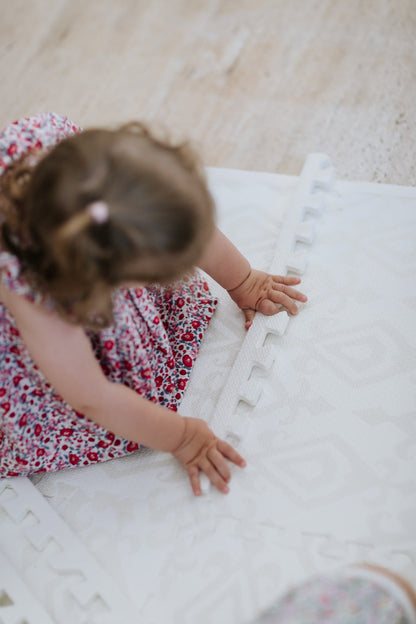 Criança brincando no tapetinho Ikat Tini Tiny — seguro, atóxico e hipoalergênico
