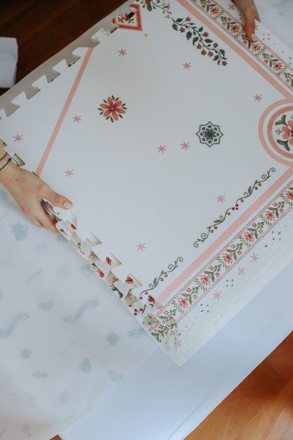 Mão encaixando uma placa no canto do tapetinho Vintage Rose, com o barrado floral na borda