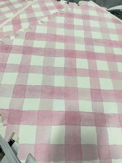 Close das placas do tapete infantil de EVA Criss Cross rosa montadas, com o xadrez aquarelado, a textura do EVA e os encaixes na borda
