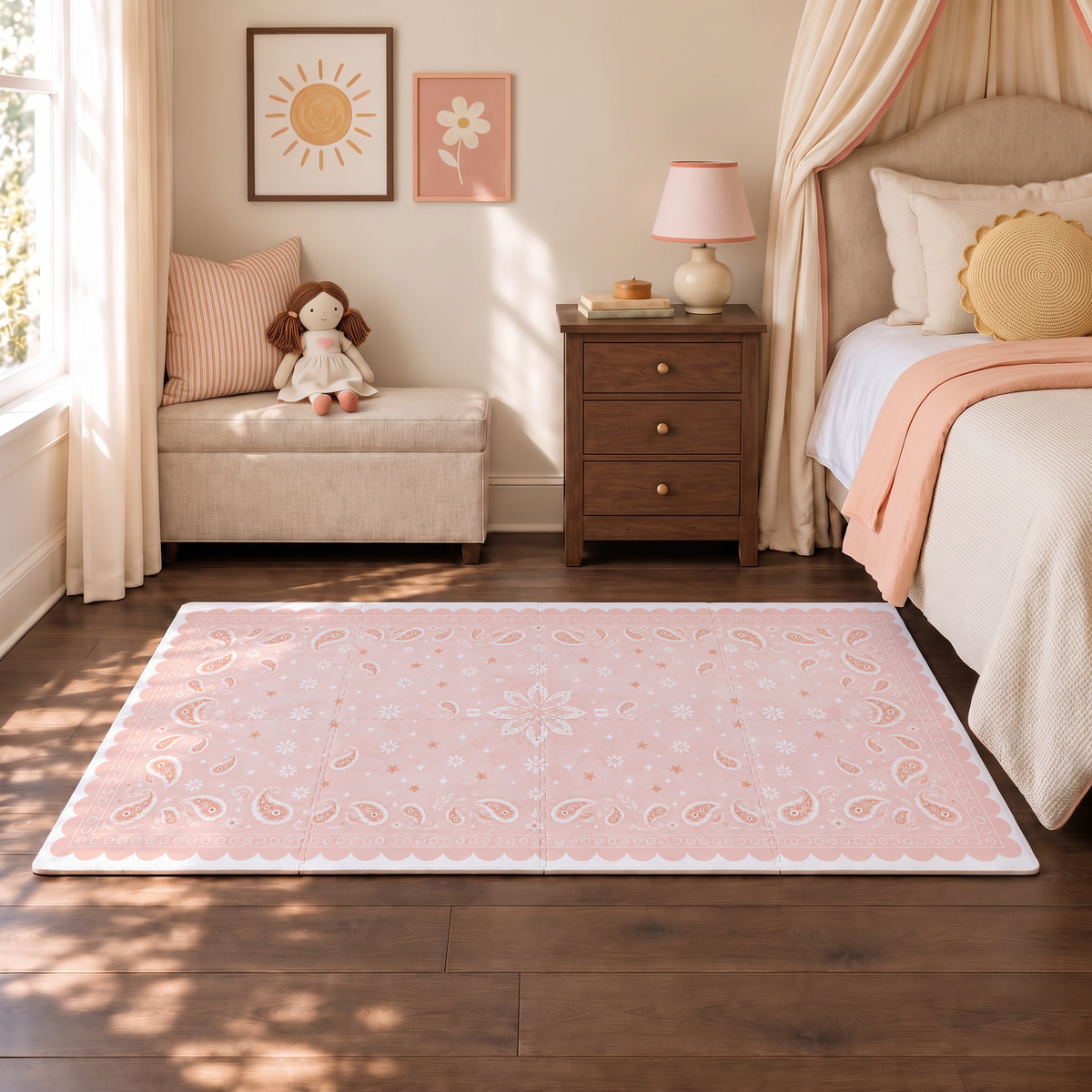 Tapete infantil de EVA Bandana rosa no quarto, ao lado da cama com manta rosa, banco com boneca de pano e quadrinhos de sol e flor na parede