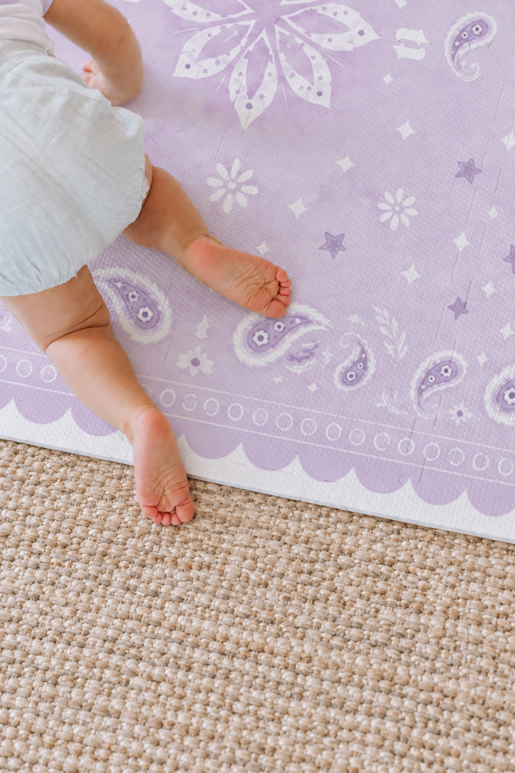 Bebê de roupinha clara de bruços no tapete infantil de EVA Bandana lilás, com a flor central, paisleys e a borda ondulada, sobre tapete de sisal