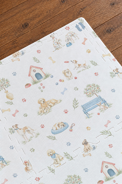 Close do canto do tapete infantil de EVA Toile de Jouy Dogs multicolorido montado sobre piso de madeira, com casinha vermelha, banco azul, caminha azul, cachorrinhos em aquarela e os encaixes das placas