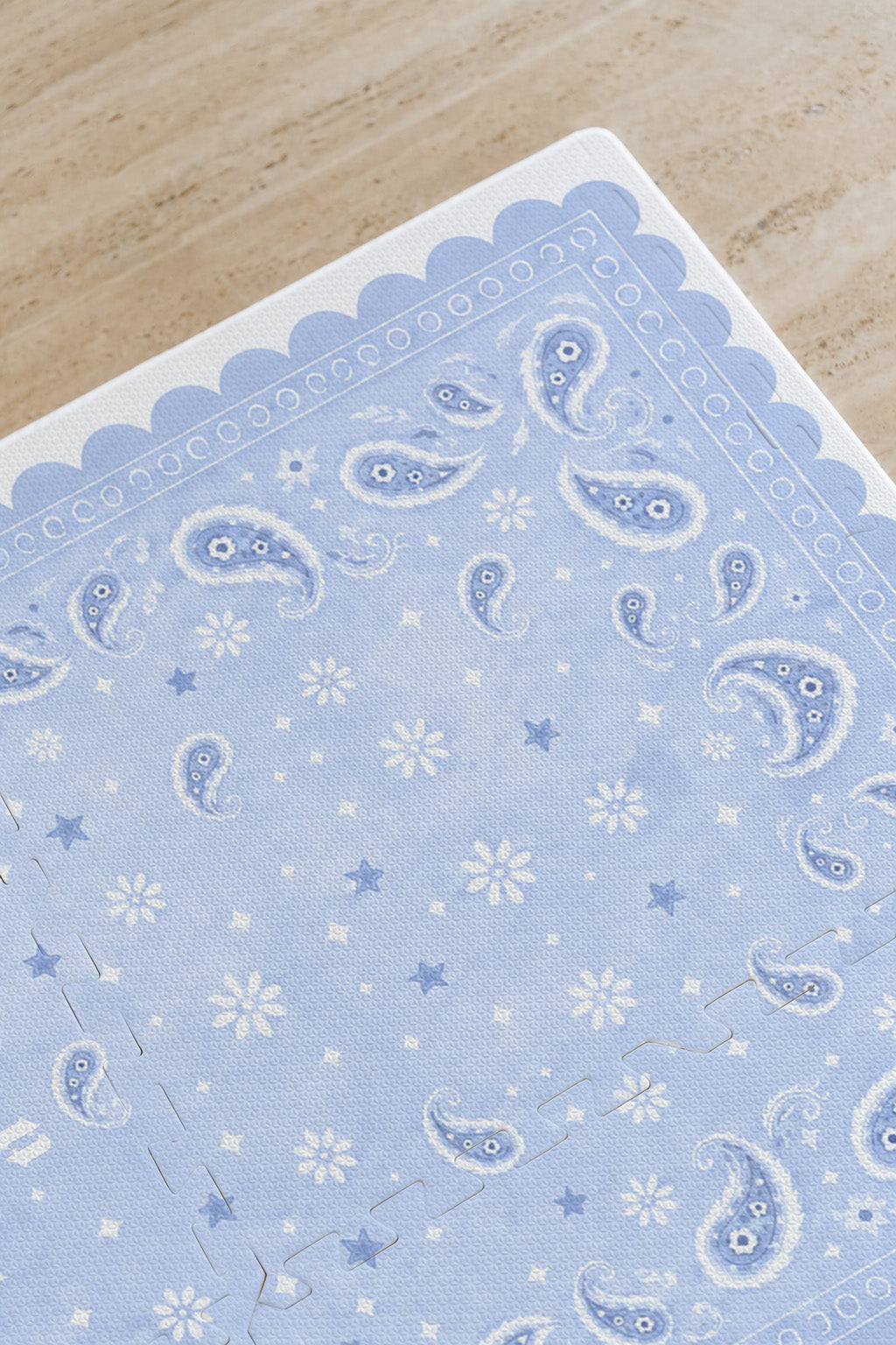Detalhe do canto do tapete infantil de EVA Bandana azul, com paisley, florzinhas, estrelinhas e borda ondulada