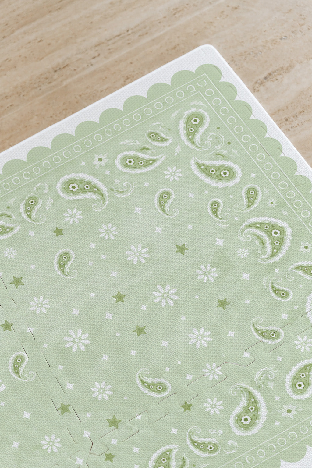 Detalhe do canto do tapete infantil de EVA Bandana verde, com paisley, florzinhas, estrelinhas e borda ondulada