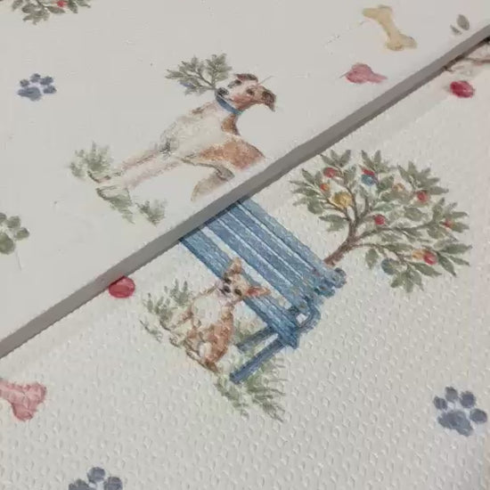 Vídeo de perto das placas do tapetinho Toile de Jouy Dogs multicolorido, com cachorrinhos em aquarela, banco azul, arvorezinhas, ossinhos e patinhas coloridas