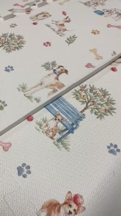 Vídeo de perto das placas do tapetinho Toile de Jouy Dogs multicolorido, com cachorrinhos em aquarela, banco azul, arvorezinhas, ossinhos e patinhas coloridas
