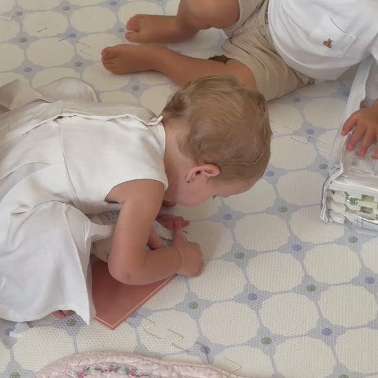 Vídeo de duas crianças brincando sentadas no tapete infantil de EVA Flower Power azul, com um livrinho