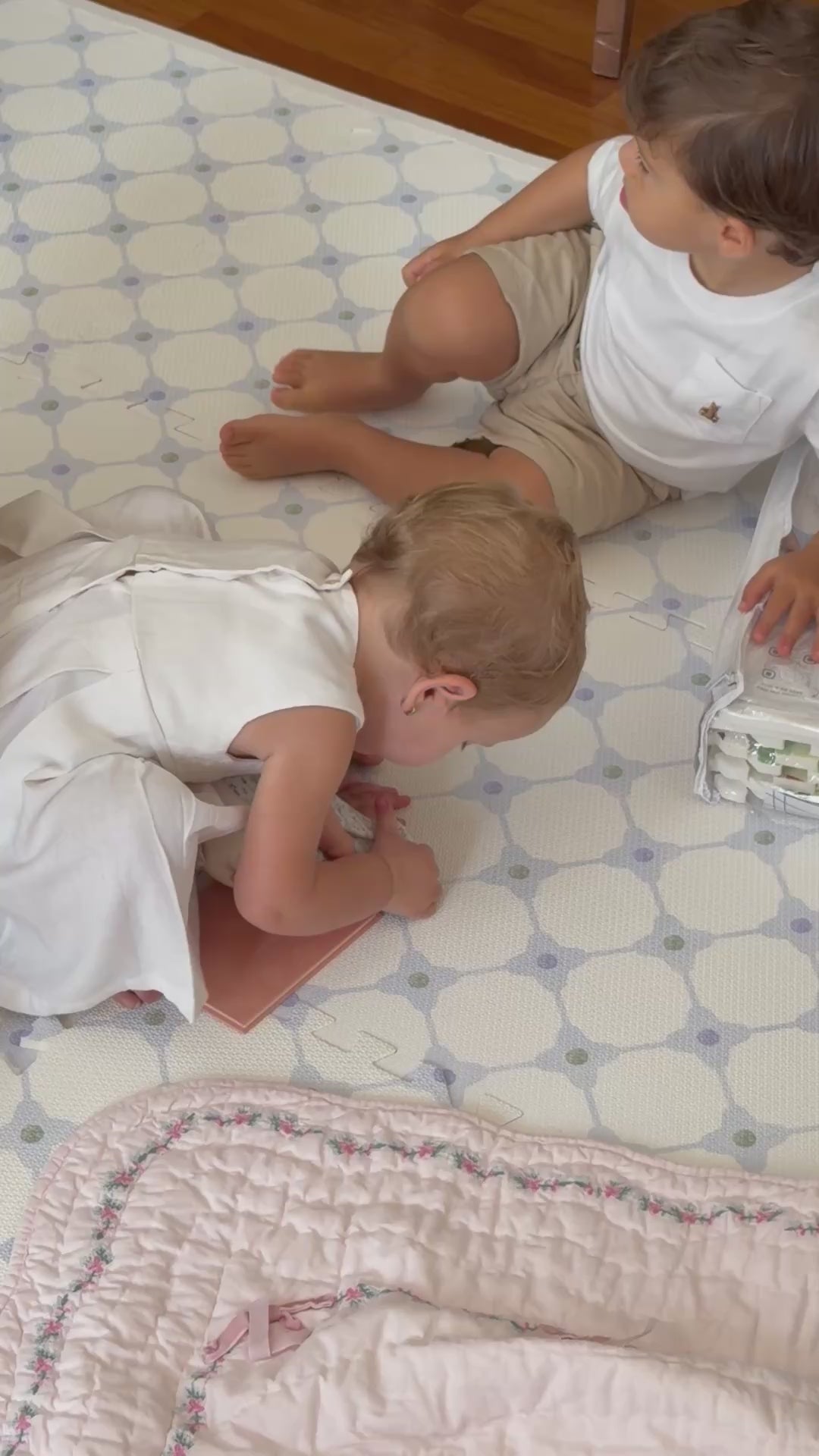 Vídeo de duas crianças brincando sentadas no tapete infantil de EVA Flower Power azul, com um livrinho
