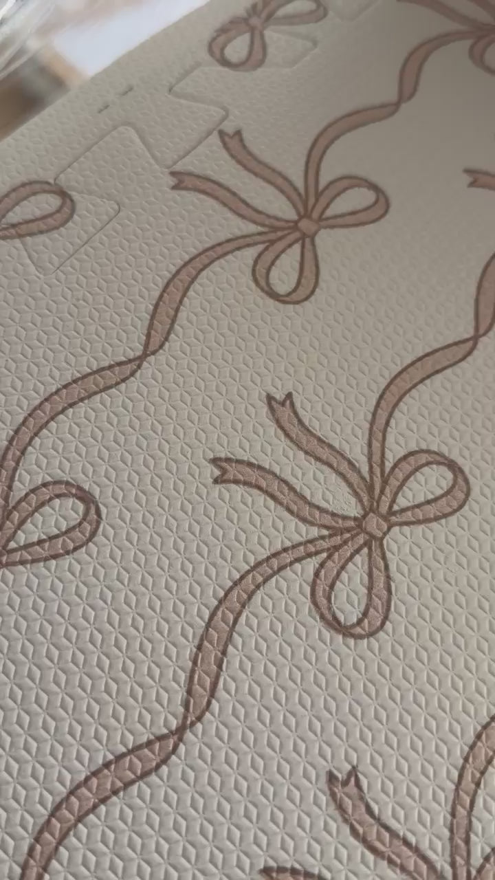 Vídeo de perto do tapetinho Tiny Bows rosa montado, com as fileiras de lacinhos ligados pela fita fina