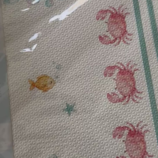 Vídeo das placas do tapetinho Ariel saindo do plástico, com a borda verde, bolhas e caranguejos