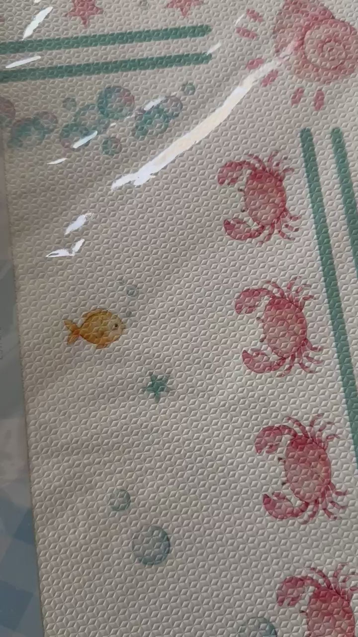 Vídeo das placas do tapetinho Ariel saindo do plástico, com a borda verde, bolhas e caranguejos