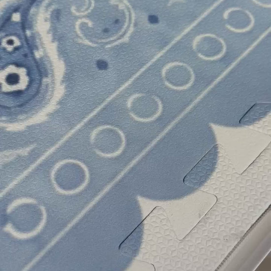 Vídeo de mão mostrando de perto a borda ondulada e o paisley do tapetinho Bandana azul