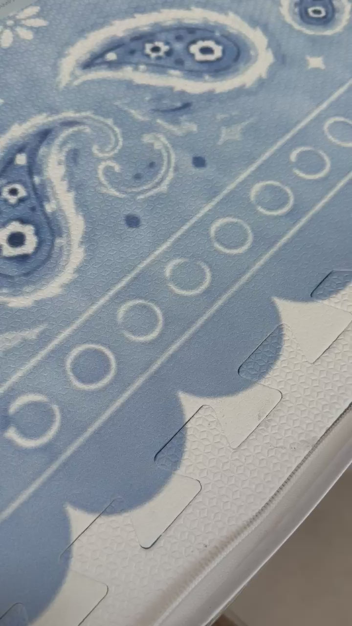 Vídeo de mão mostrando de perto a borda ondulada e o paisley do tapetinho Bandana azul